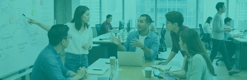 Varias personas trabajando en una mesa y una pizarra